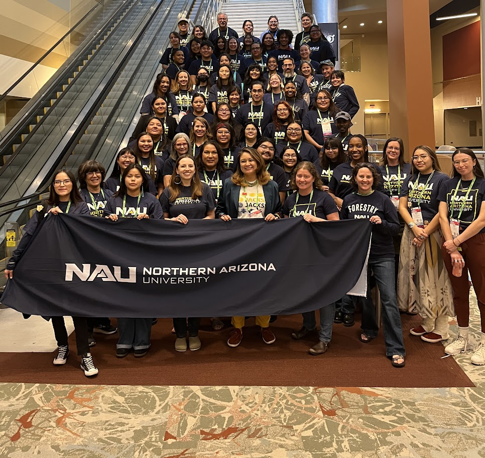 Students stand on staircase in front of NAU banner